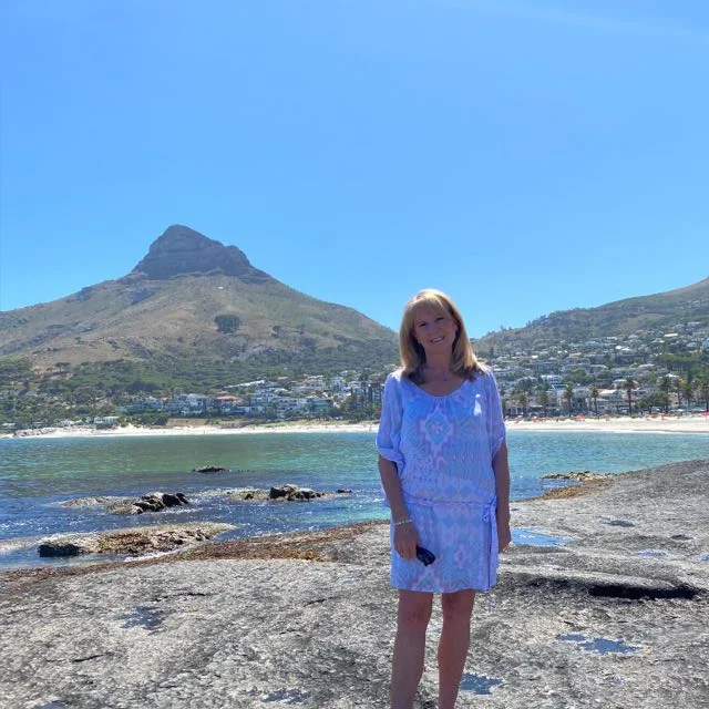 Thelma Sandeman on the rocks at Camps Bay, with Lion's Head behind her